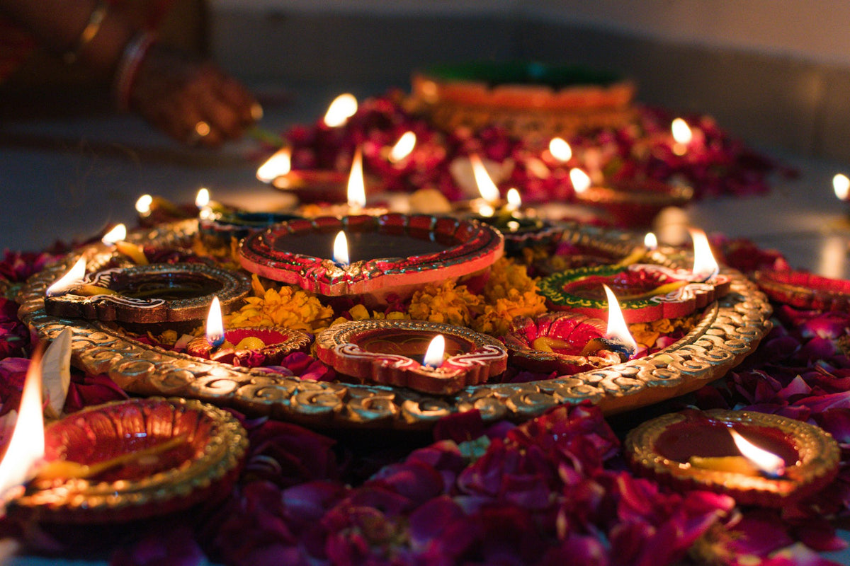 Lit clay oil lamps and marigold petals on a decorative tray for Diwali